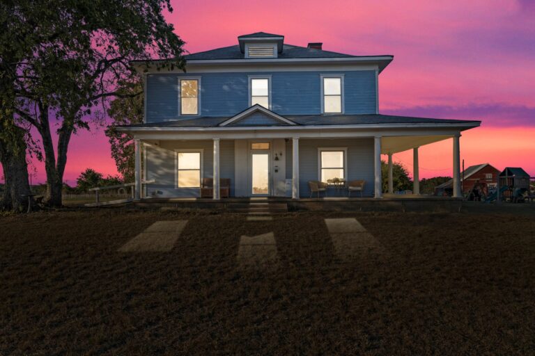 Beautiful historic farmhouse for sale in Durant, OK, featuring 52 acres of scenic rolling hills, a classic red barn, and a spacious 5-bedroom remodeled home with modern amenities and country charm.